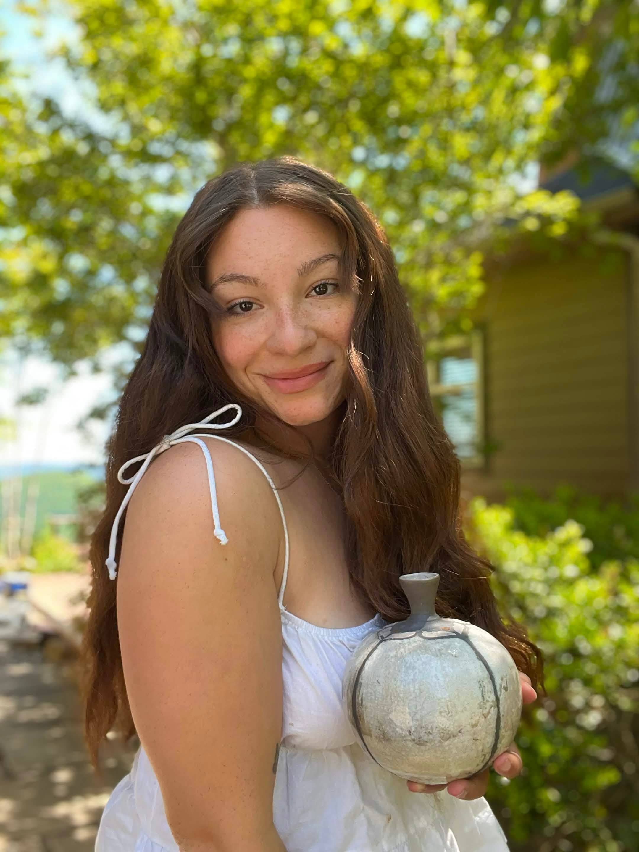 Kay outdoors holding a small round vessel